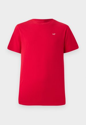 Red cotton t-shirt with short sleeves and a round neckline. Features a small white logo on the left chest area. Plain design.