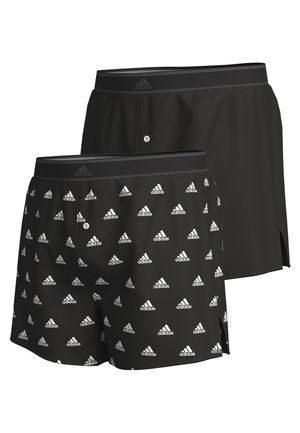 Černé sportovní šortky s bílým opakujícím se vzorem loga Adidas, elastickým pasem a bočními rozparky pro větší pohyblivost a pohodlí.