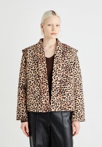 Leopardprint jakke med myk tekstur, dristig mønster og strukturert krage. Kombinert med en brun topp og sorte skinnbukser.