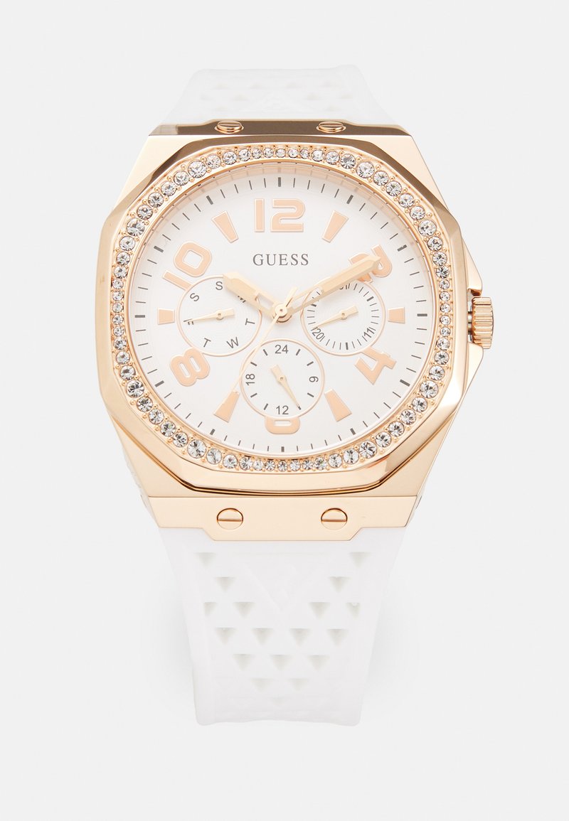 Montre en silicone blanc avec un boîtier octogonal en or rose, accents en cristal, un cadran blanc, de gros chiffres et trois sous-cadrans pour le jour et l'heure.