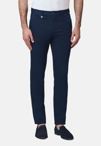 Granatowe chinosy wykonane z bawełny. Smukły krój z płaskim przodem, bocznymi kieszeniami oraz zapięciem na guzik z przodu. Miękka tekstura.