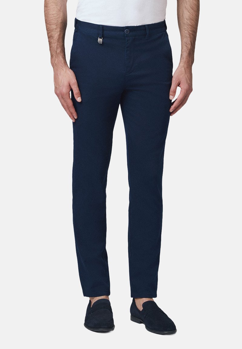 Granatowe chinosy wykonane z bawełny. Smukły krój z płaskim przodem, bocznymi kieszeniami oraz zapięciem na guzik z przodu. Miękka tekstura.