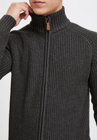 Dunkelgrauer, gestrickter Reißverschluss-Pullover mit hohem Kragen, der über eine gerippte Textur und einen Holz-Reißverschlussanhänger verfügt.
