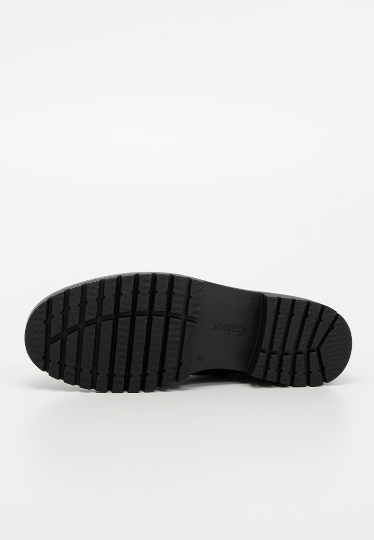 Schwarze Gummisohle mit horizontalen und vertikalen Rillen für besseren Halt. Sie verfügt über eine glatte Ferse und ein abgerundetes Zehen-Design für zusätzlichen Komfort.