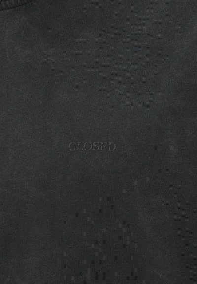 Tumman harmaa puuvillahihaton t-paita, jossa on rib-tekstuuri ja pieni kohokuvioitu "CLOSED" -labeli edessä. Yksinkertainen, pyöreä pääntie.