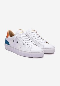 Zapatillas de cuero blancas con un diseño de caña baja, que presentan un acento azul y naranja en el talón, y una suela de goma blanca texturizada.