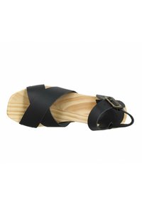 Sandale en cuir noir avec des sangles croisées, semelle en bois et accent de boucle. Design à bout carré, mettant en valeur une texture lisse et un grain de bois naturel.