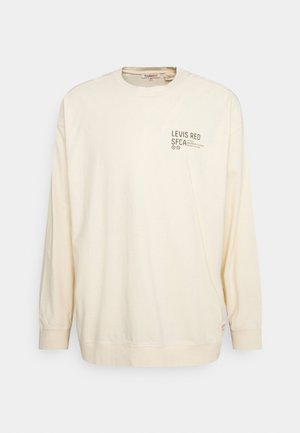 Krémová košile s dlouhým rukávem vyrobená z bavlny, s malým tištěným logem na levé přední straně a volným střihem.