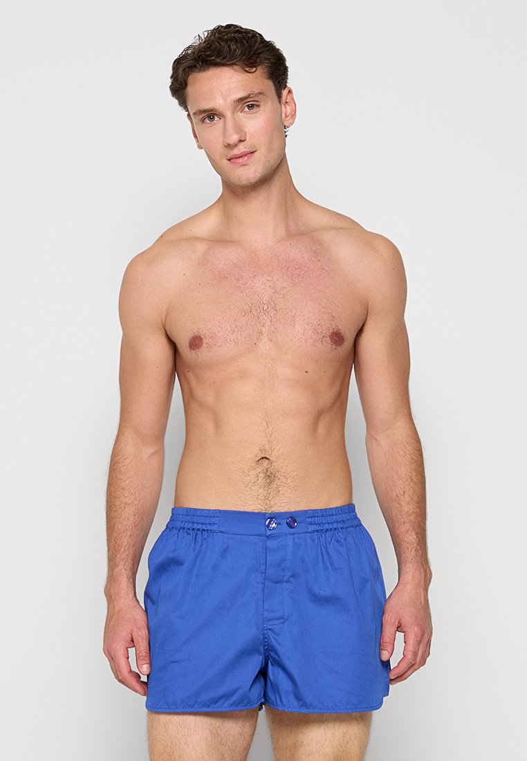 Bañador azul con cintura elástica y dos botones en el frente; material suave y ligero; longitud a medio muslo.