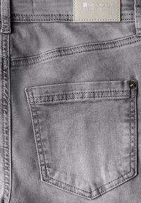 Gray denim fabric with a visible back pocket, accented by contrasting stitching and a rectangular label at the waistband.