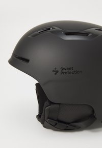 Črna čelada z mat površino, ki vsebuje prezračevalne reže, strukturirano notranjo oblogo in logo Sweet Protection na strani.