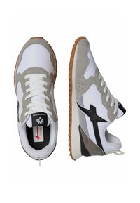 Scarpe sportive bianche e grigie con una parte superiore in suede e sintetico, suola in gomma, lacci e un logo nero sul lato.