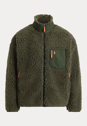 Veste en polaire sherpa vert olive avec fermeture éclair complète, col montant, poche poitrine zippée avec tirette orange et poches latérales zippées.
