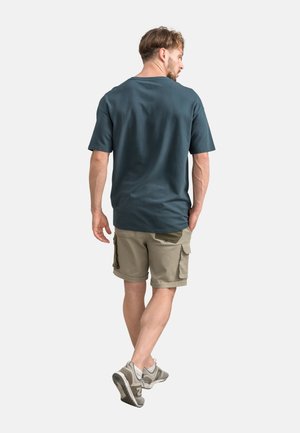 Donkerblauwe t-shirt met korte mouwen, losse pasvorm, gecombineerd met lichte khaki cargoshorts met zakken, aangevuld met grijze sportschoenen.