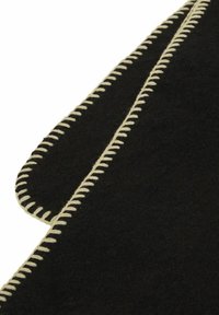 Material de fieltro negro con costuras de crema contrastantes a lo largo de los bordes; presenta una forma irregular con una textura suave y líneas limpias.