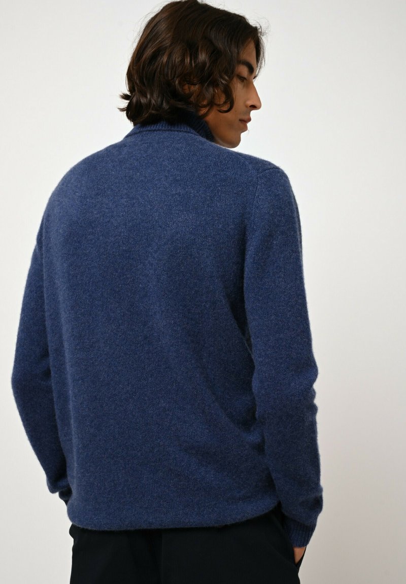 Granatowy sweter o miękkiej fakturze, z prążkowanym kołnierzem i długimi rękawami. Zaprojektowany w luźnym kroju, z minimalną liczbą szwów.