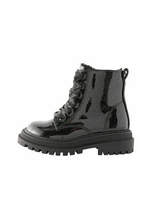 Botte de combat noire brillante avec semelle épaisse à crampons et lacets en ruban de satin, vue de côté sur fond blanc.