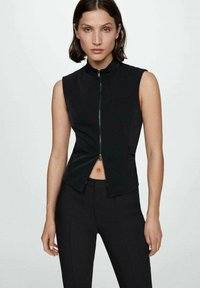 Gilet nero senza maniche con collo alto, zip frontale e vestibilità su misura. Tessuto liscio con una leggera lucentezza, caratterizzato da un design pulito.