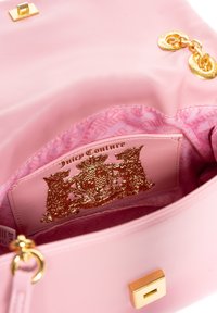 Borsa rosa con un esterno liscio, hardware dorato e un interno in tessuto a fantasia. Presenta una patch con logo dorato e una chiusura quadrata.