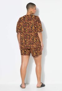 T-shirt met korte mouwen en korte broek in een bruin, geel en zwart dierenprintpatroon. Gemaakt van lichtgewicht stof en heeft een relaxed fit.
