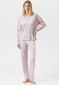 Ensemble de pyjama rose clair en tissu doux, composé d'un haut à manches longues, coupe ample, orné de gros pois blancs, et d'un pantalon assorti.