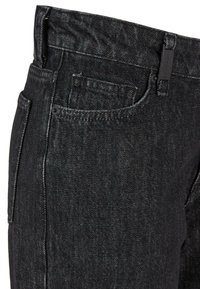 Jeans de mezclilla negra con corte recto, que cuentan con un bolsillo frontal, una textura sutil y una etiqueta de marca en la cintura.