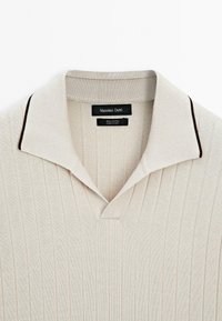 Polo en coton côtelé beige clair avec bordure marron au col, étiquette Massimo Dutti, fabriqué en Chine.