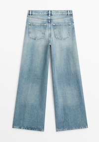 Lyseblå denimjeans med vide ben, set bagfra med to baglommer og synlige syningsdetaljer.