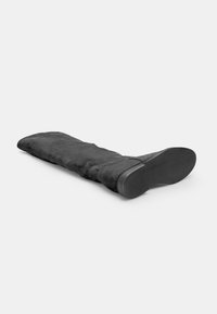 Bota de ante negra por encima de la rodilla con suela plana de goma. El eje es liso con una ligera curvatura en la parte superior. La suela presenta una textura estriada.