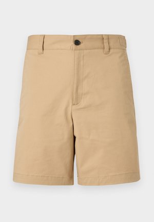 Shorts beige cintrés avec fermeture à boutons, passants pour ceinture et devant plat, conçus pour une tenue décontractée ou semi-formelle.