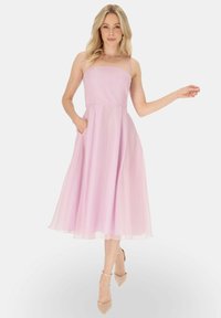 Jasnoróżowa, bezrękawna sukienka midi z dopasowaną górą, zwiewnym dołem i kieszeniami. Gładki materiał o subtelnej połysku.
