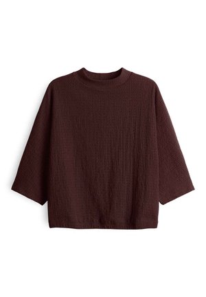 T-shirt long à manches longues de couleur marron foncé, texturé, avec un col rond et une coupe ample et carrée.