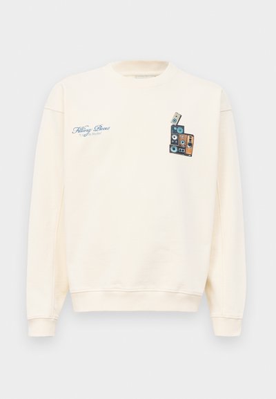 Sweatshirt de gola redonda em cor creme com texto azul "Filling Pieces" no lado esquerdo do peito e gráfico de colunas vintage empilhadas no lado direito do peito.