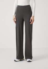 Gray ribbed wide-leg pants feature a high elastic waistband, soft texture, and flowy design, paired with white sneakers for contrast.