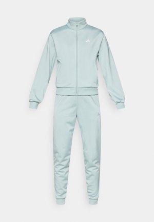 Survêtement bleu clair en tissu lisse. Comprend un col montant, une fermeture éclair intégrale et des poignets côtelés. Petit logo blanc sur la poitrine et la cuisse.