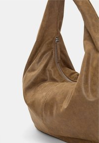 Brown leather shoulder bag with a smooth texture, hobo shape, and a side zipper detail. Features stitching along the seams.