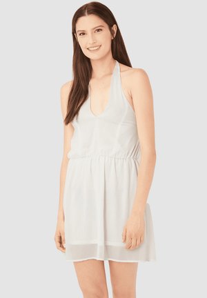 Vestido ligero y blanco con tirantes tipo halter, escote en V profundo, cintura fruncida y dobladillo a la altura de la rodilla. Confeccionado en una tela suave y transparente con una textura lisa.