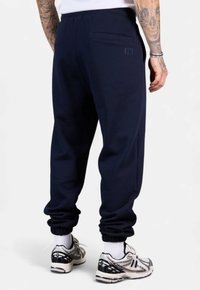 Marineblaue Sweatpants aus weichem Stoff mit lässiger Passform, elastischen Bündchen und einer Gesäßtasche mit minimalen Stickdetails.