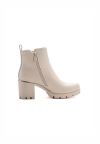 Botines beige de cuero, con cierre de cremallera lateral, tacón grueso y suela de goma texturizada con muescas.