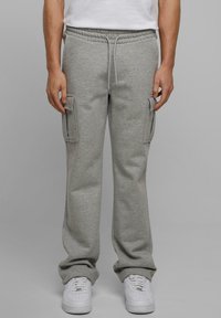 Lichtgrijze sweatpants gemaakt van een zachte katoenmix, met zijvakjes en een verstelbare koordsluiting in de taille; gecombineerd met witte sneakers.