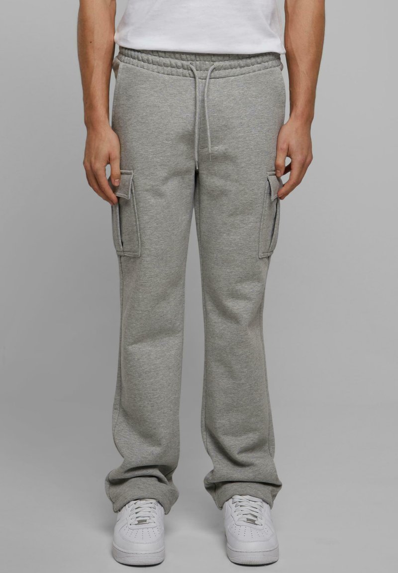 Lichtgrijze sweatpants gemaakt van een zachte katoenmix, met zijvakjes en een verstelbare koordsluiting in de taille; gecombineerd met witte sneakers.