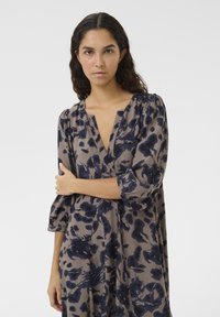 Robe à imprimé floral en beige et marine, avec un décolleté en V, des manches 3/4, une coupe décontractée et un tissu doux et fluide avec un motif texturé.