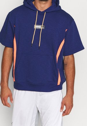 Granatowa bluza z kapturem z pomarańczowymi paskami, luźnym krojem, krótkimi rękawami oraz przednią kieszenią kangurka. Regulowany kaptur ze sznurkiem.