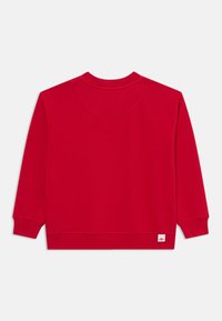 Roter Sweatshirt mit langen Ärmeln, rundem Halsausschnitt und gerippten Bündchen. Mit einem kleinen Etikett am unteren Saum. Weiches Baumwollmaterial.