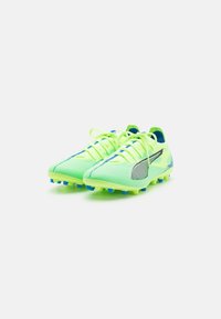 Scarpette da calcio verde neon con un design leggero in rete, tomaia testurizzata, accenti blu e tacchetti conici per una migliore aderenza sul prato artificiale.