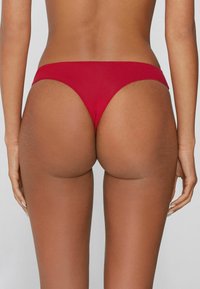 Czerwone bikini o gładkiej tkaninie, z minimalistycznym wzorem, wysokim wycięciem nogawek i niskim stanem.