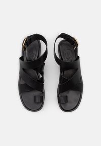 Černé kožené sandály s otevřenou špičkou, několika překrývajícími se pásky a zlatou sponou pro bezpečné uchycení. Plochá podrážka s texturovanou stélkou.