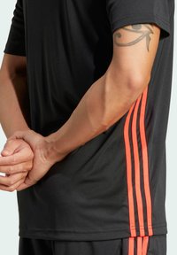adidas Performance TIRO ESSENTIALS - Tekninen t-paita - black lucid red