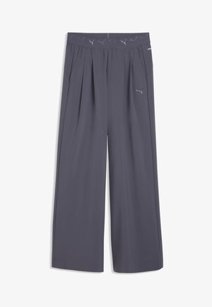 Pantalon gris large Puma avec taille élastique comportant des logos Puma répétés et des poches latérales.