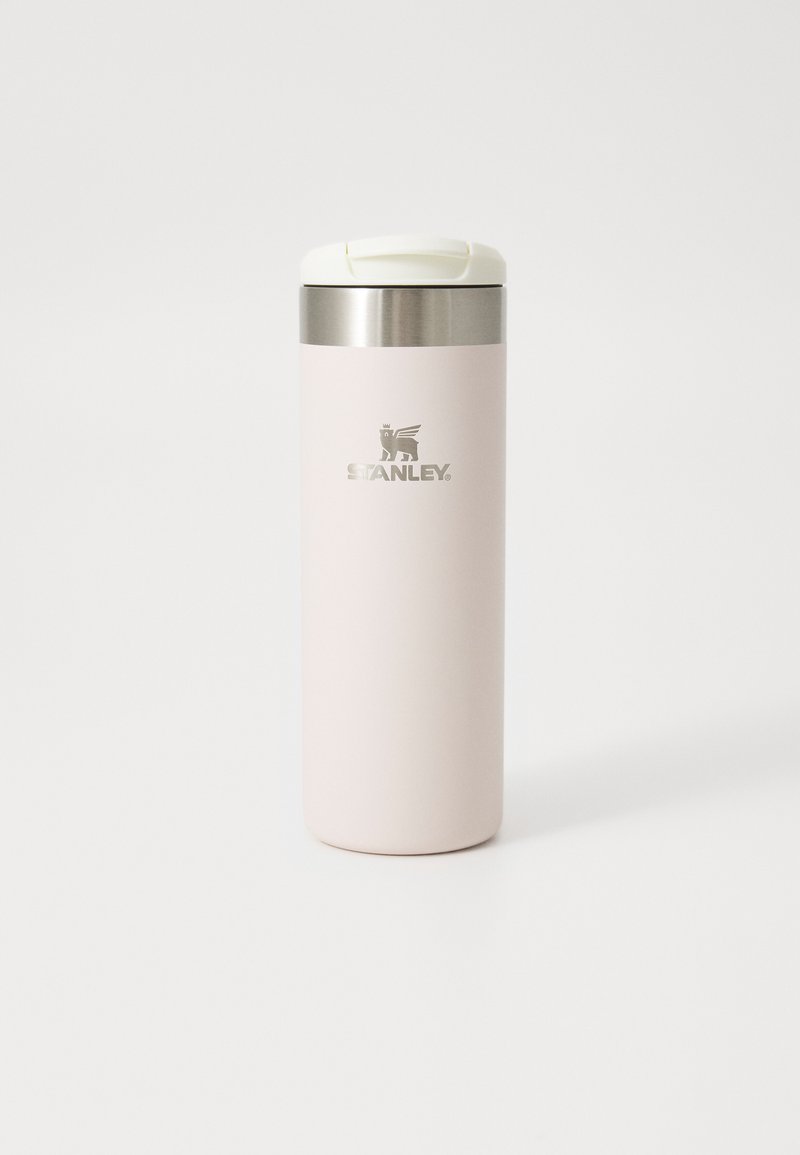 Gobelet de voyage en acier inoxydable avec une finition mate rose doux, un couvercle blanc et un logo Stanley gravé. Forme cylindrique, design élégant.